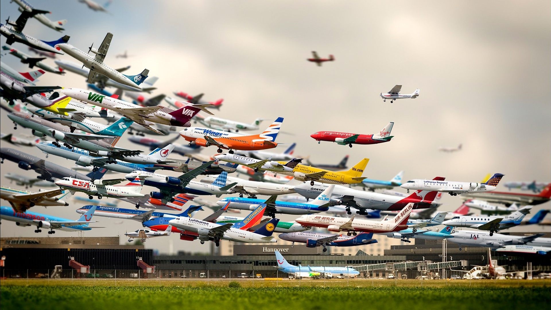 Many airplanes flying over an airport HD Wallpaper