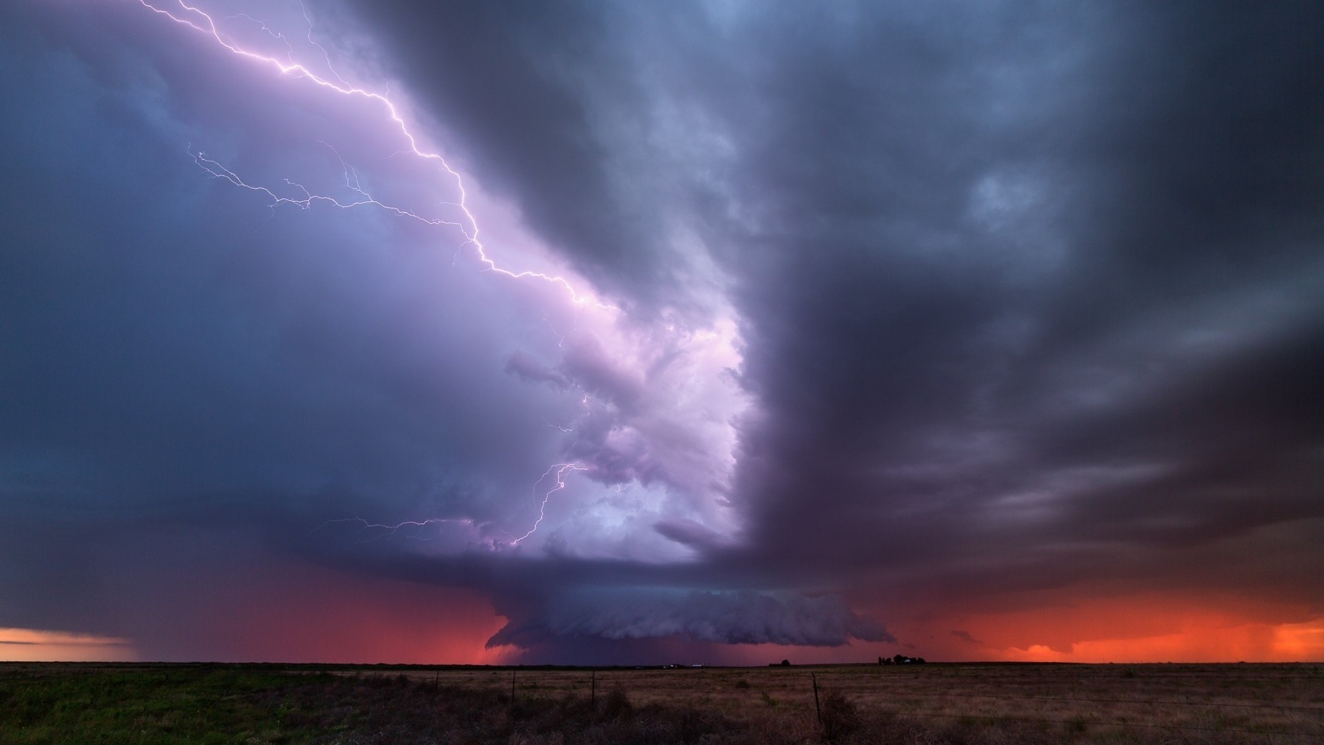 Lightning strikes a supercell thunderstorm over a field HD Wallpaper