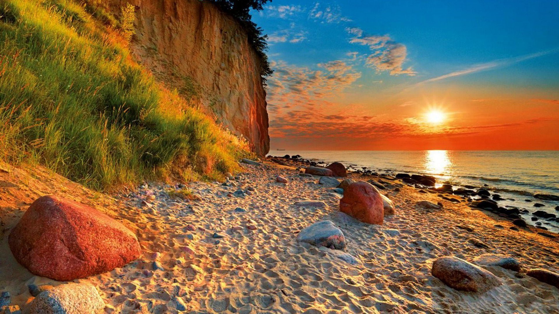 Sunset over the ocean with a cliff and beach HD Wallpaper