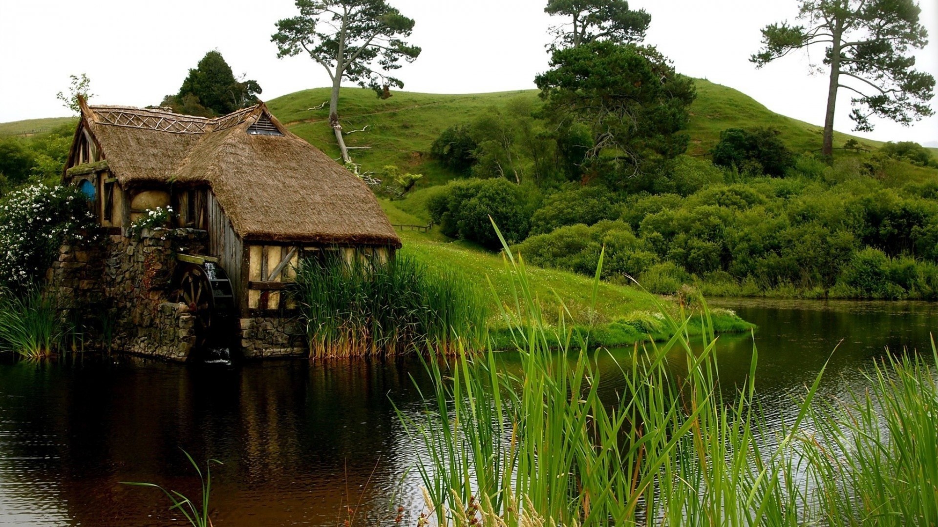 Old mill by a lake with rolling hills HD Wallpaper