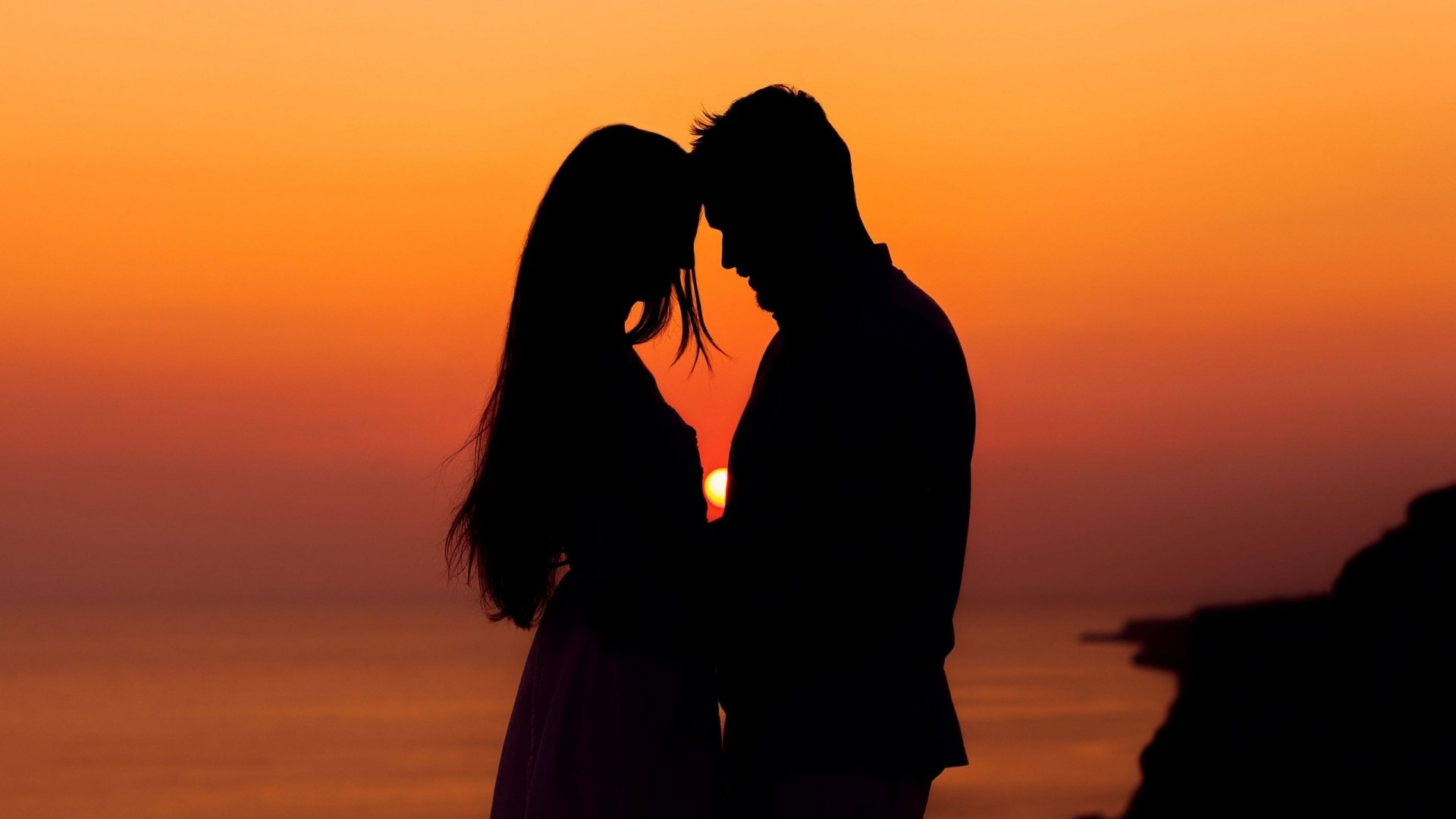 Couple silhouetted against a sunset HD Wallpaper