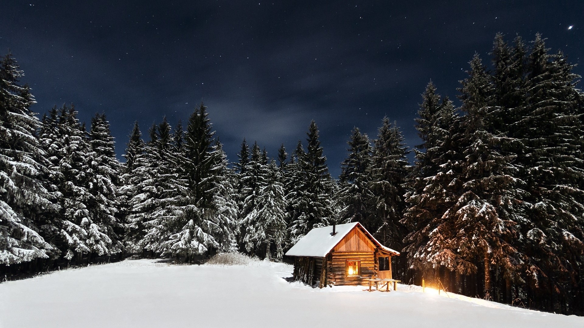 Wooden cabin in snowy forest at night HD Wallpaper