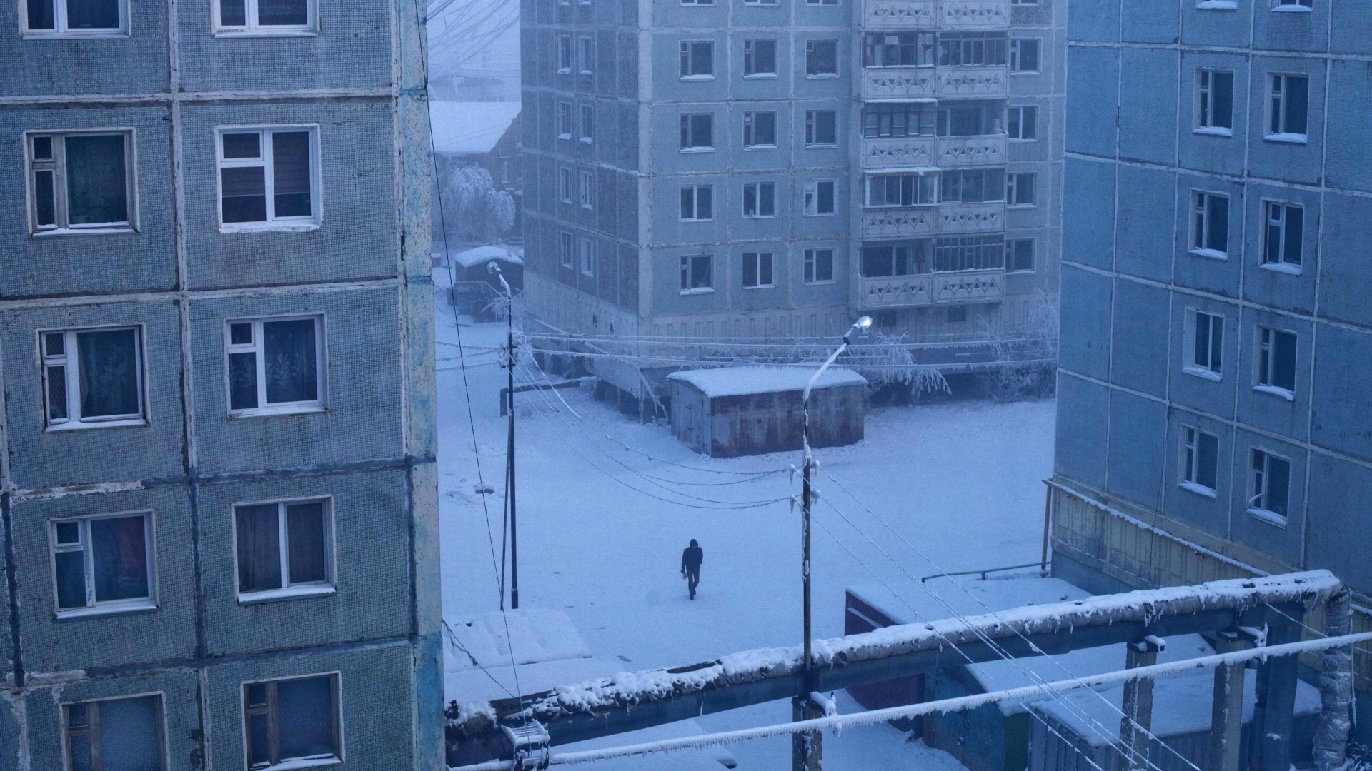 A person walks through a snowy courtyard in Yakutsk HD Wallpaper