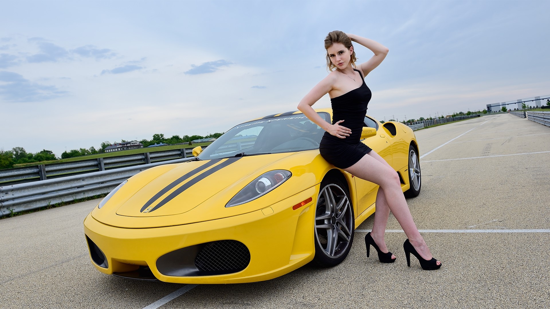 Girl posing with a yellow Ferrari on a racetrack HD Wallpaper