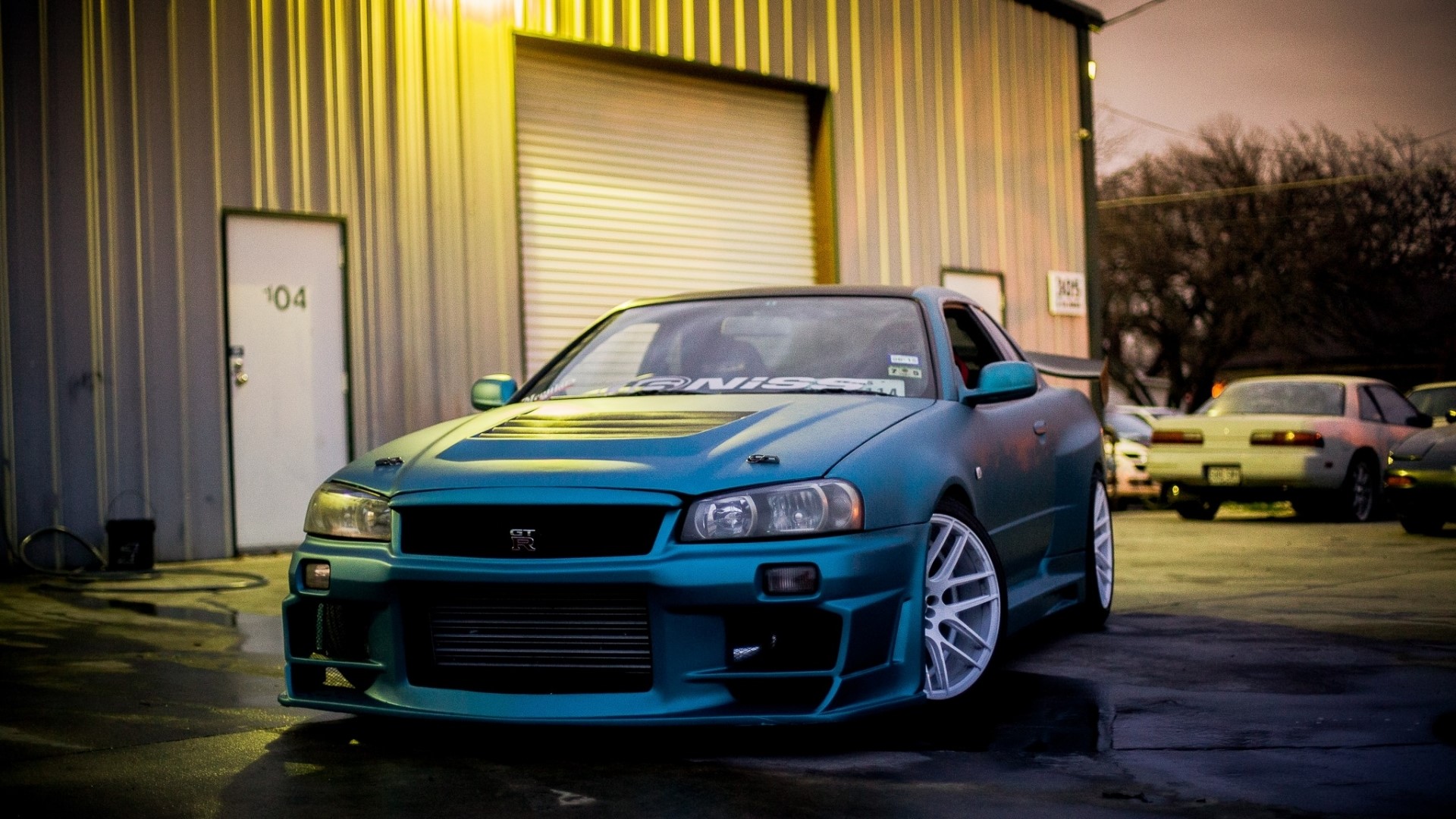 Nissan GT-R R34 in front of a building HD Wallpaper