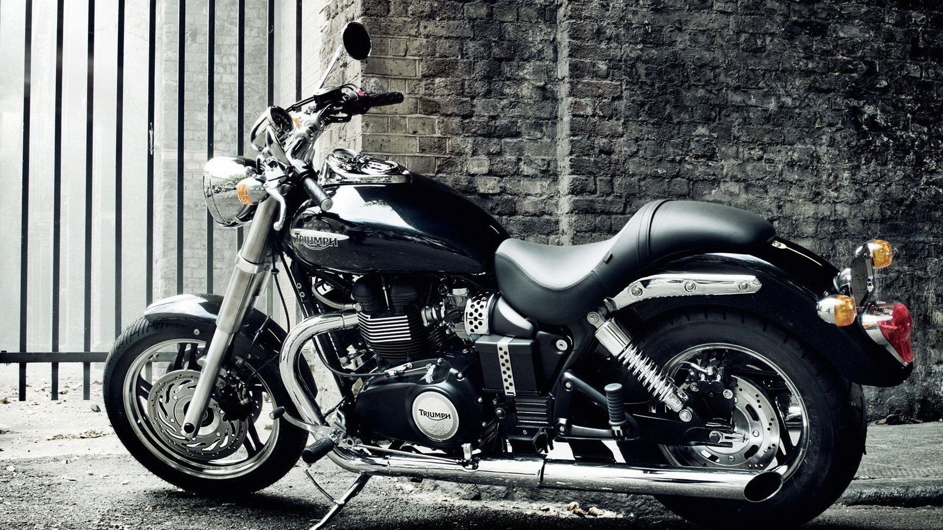 Black Triumph Motorcycle parked by brick wall HD Wallpaper