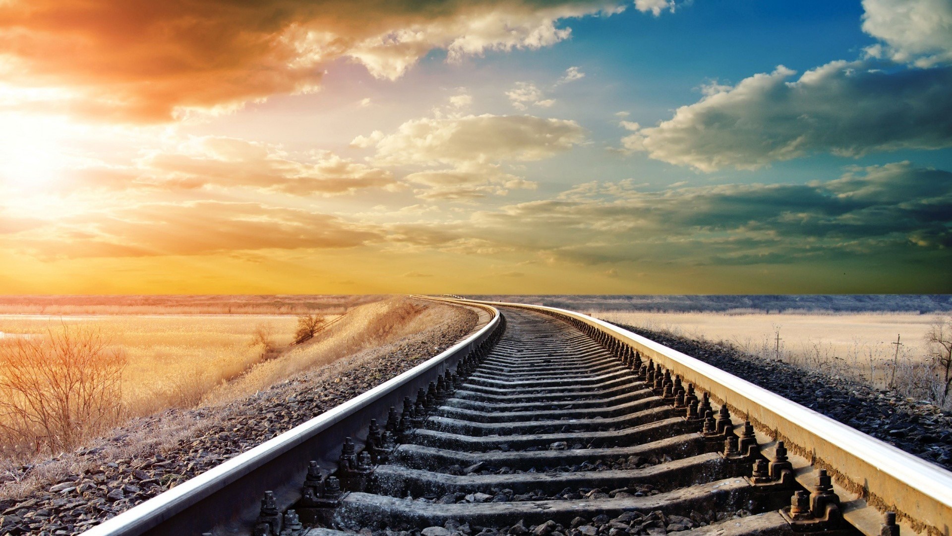 Railroad tracks crossing a prairie at sunset HD Wallpaper