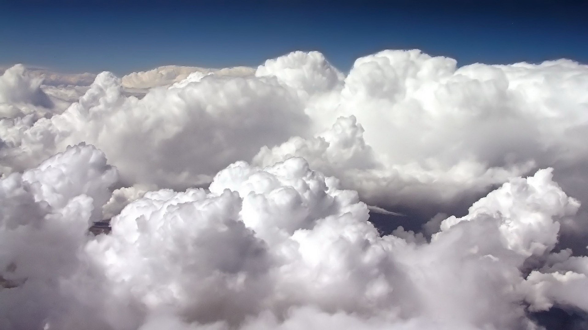 Fluffy white clouds against a deep blue sky HD Wallpaper