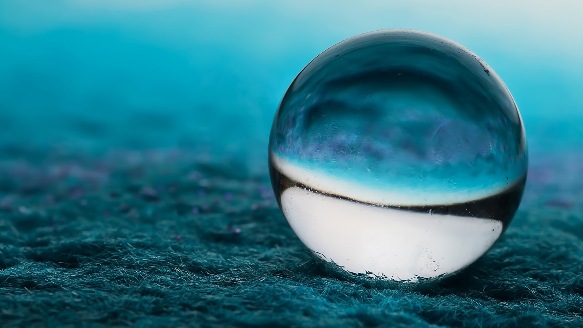 Close up of a blue glass ball on a textured surface HD Wallpaper