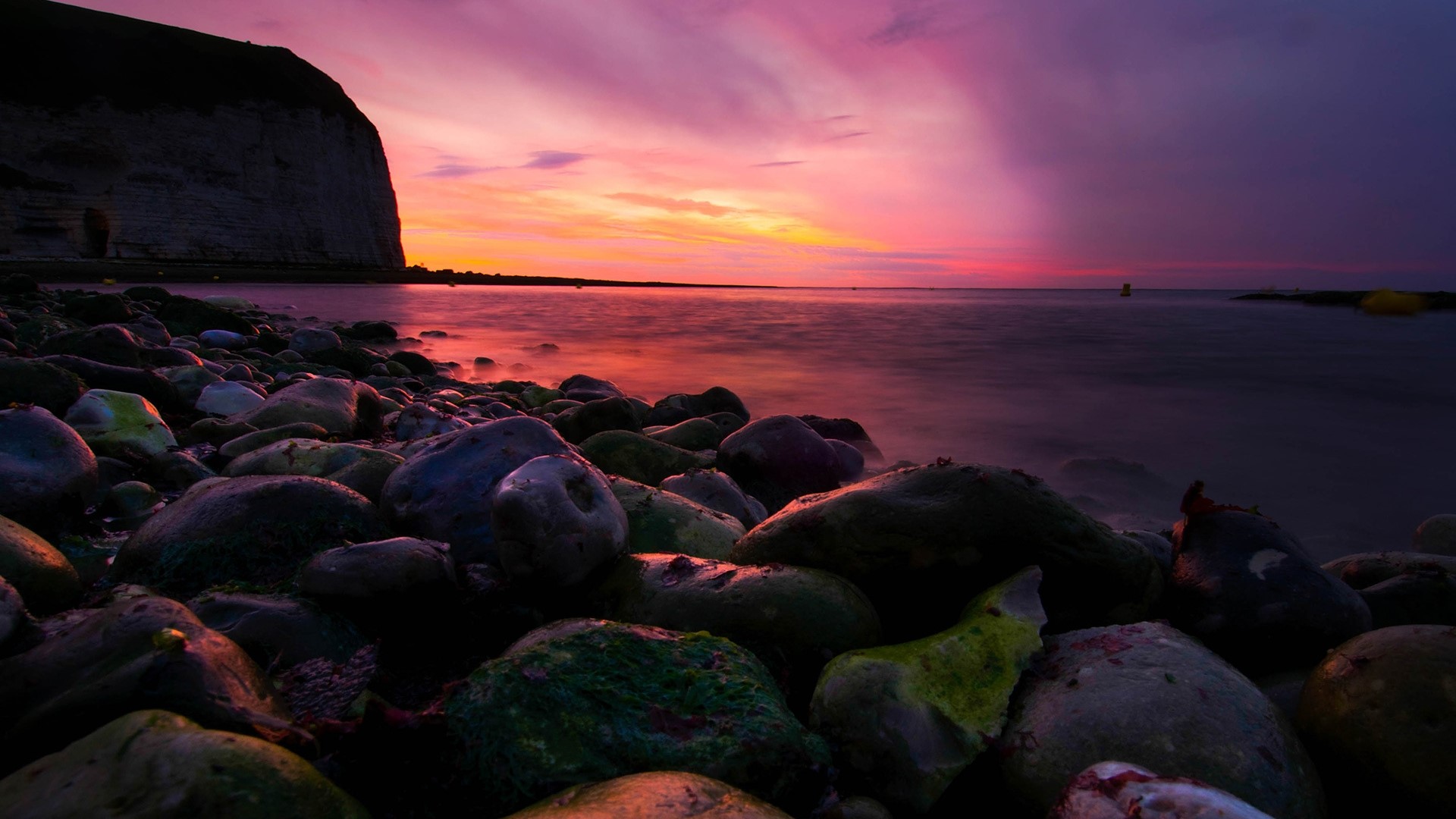 Rocky beach at sunset with purple and orange sky HD Wallpaper