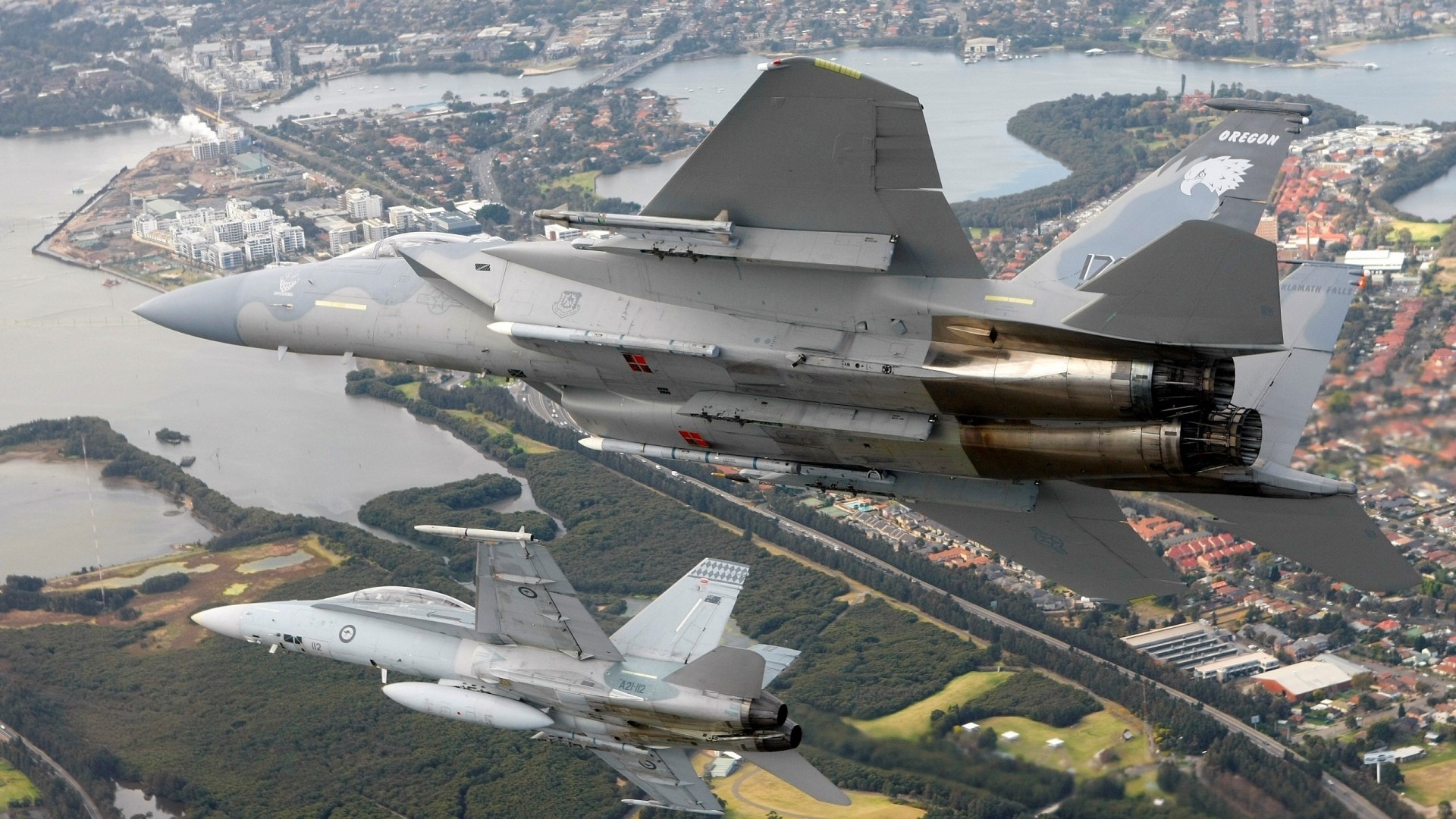 F-15 Eagle and F/A-18 Hornet in flight over city HD Wallpaper