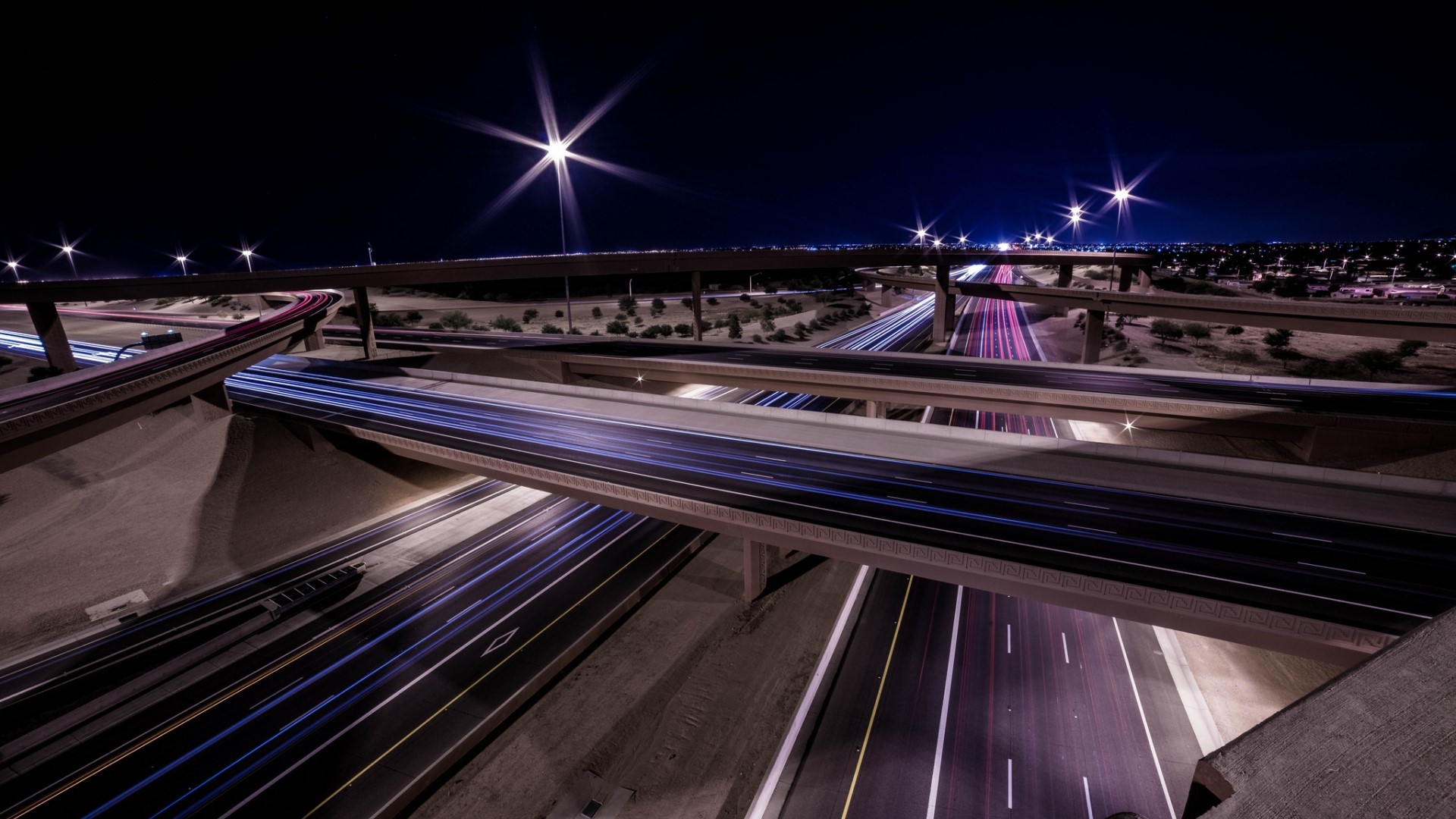 Nighttime highway interchange with light trails HD Wallpaper