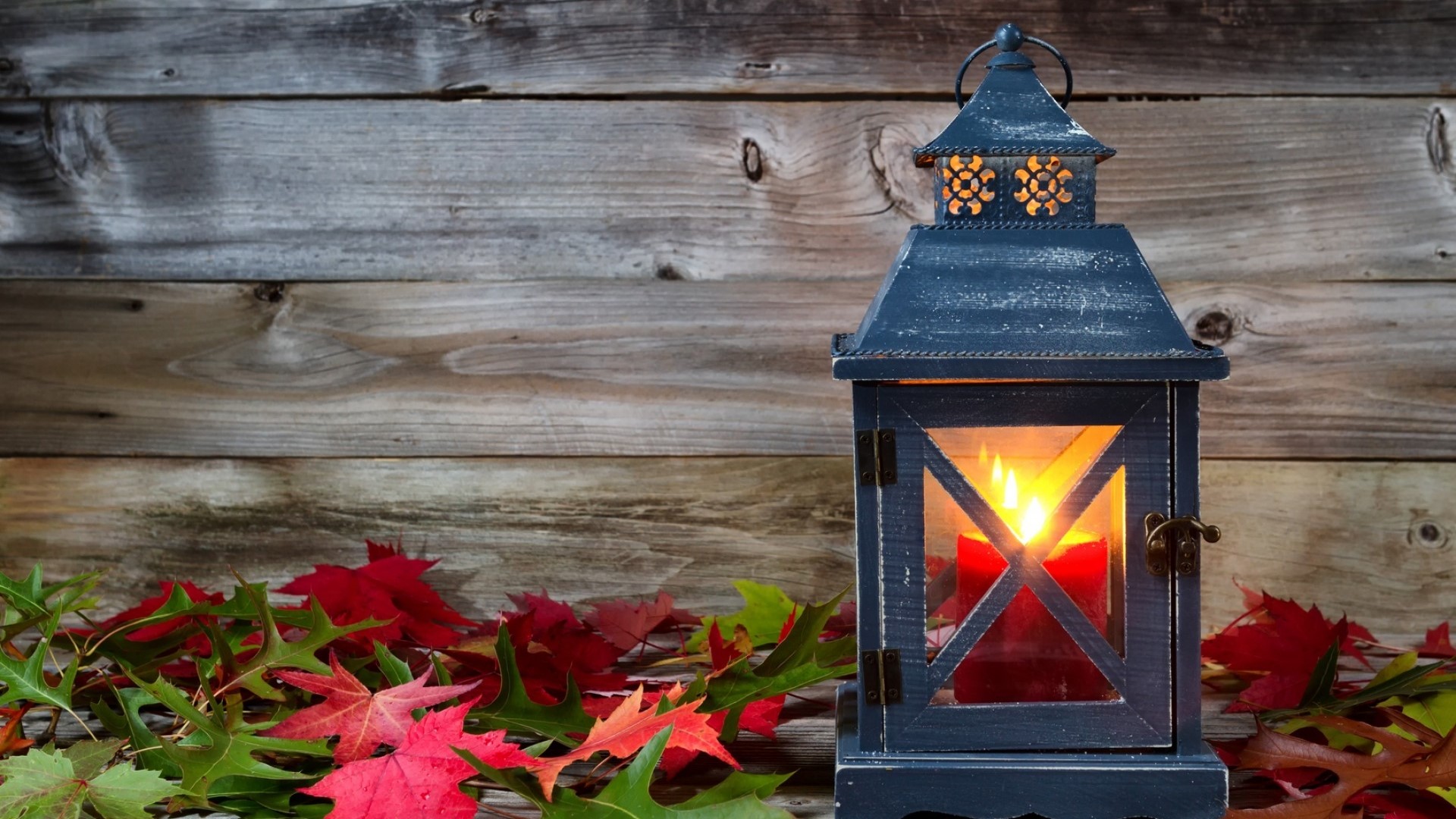 Lantern with candle and autumn leaves on wooden background HD Wallpaper