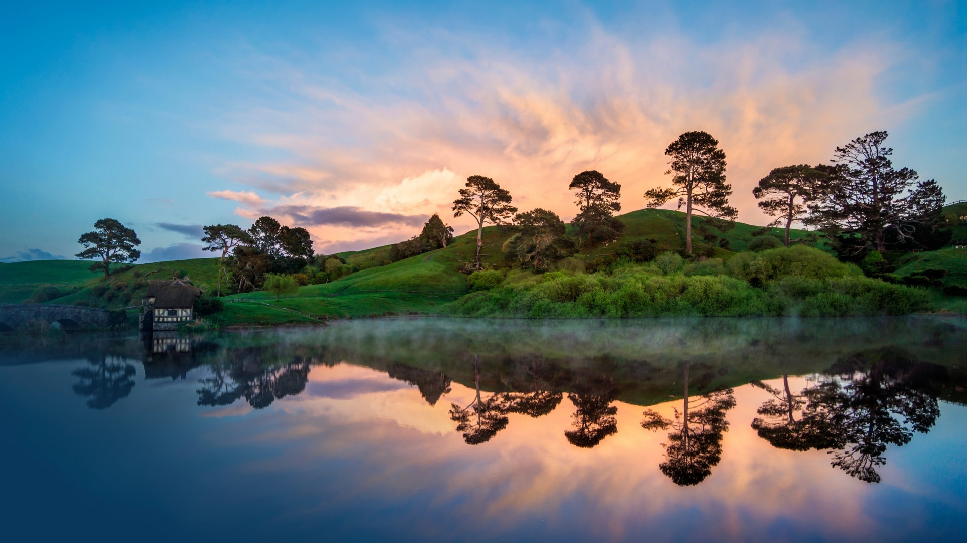 Hobbiton house reflected in a misty lake at sunrise HD Wallpaper