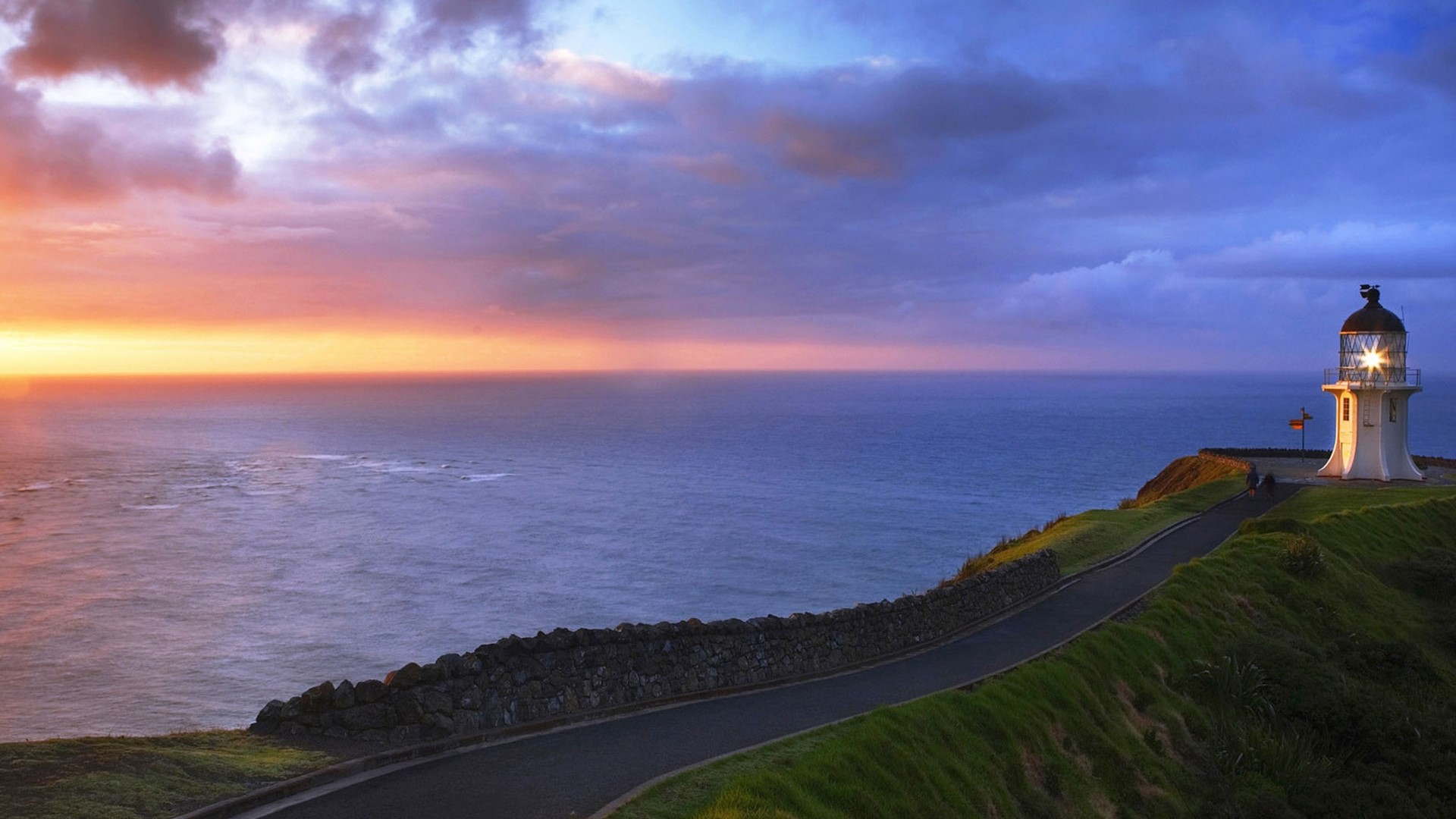 Road to lighthouse at sunset over the ocean HD Wallpaper