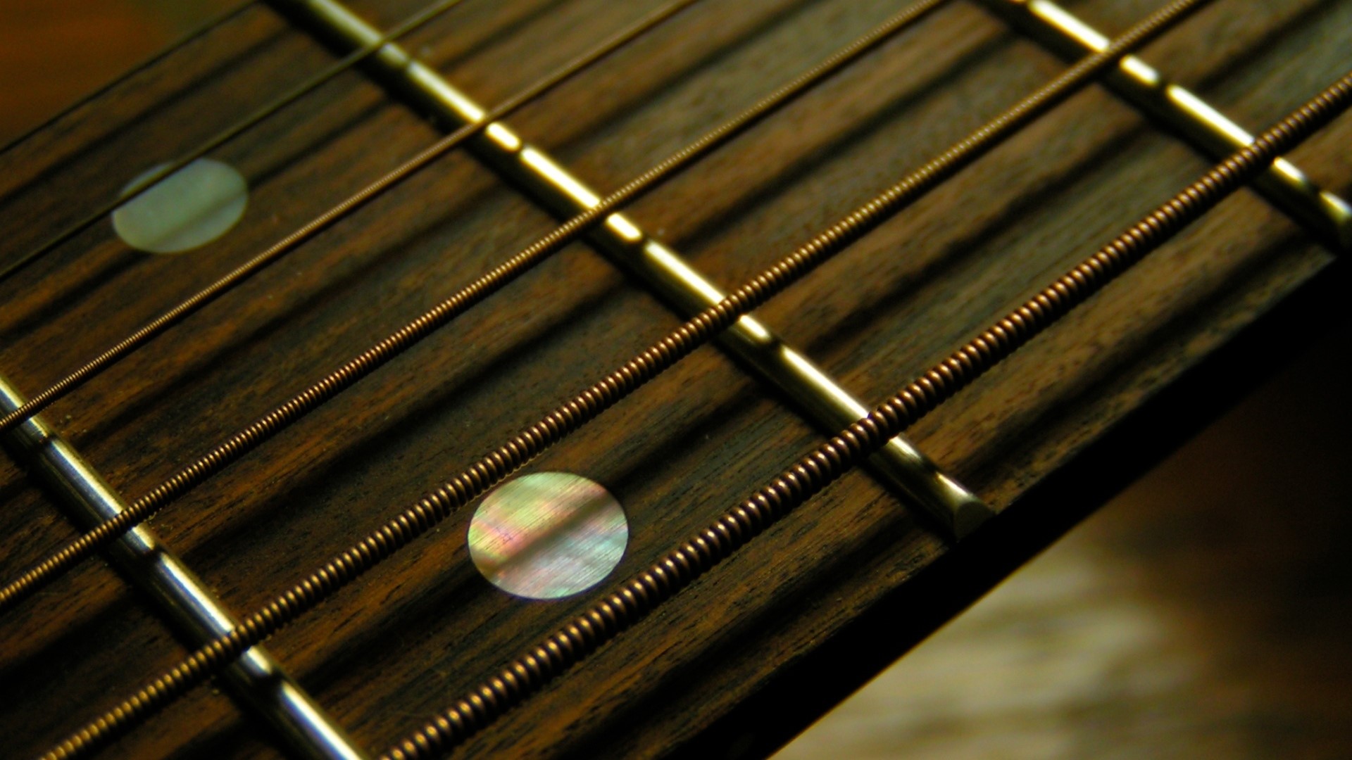 Close-up of a guitar fretboard with strings and inlays HD Wallpaper