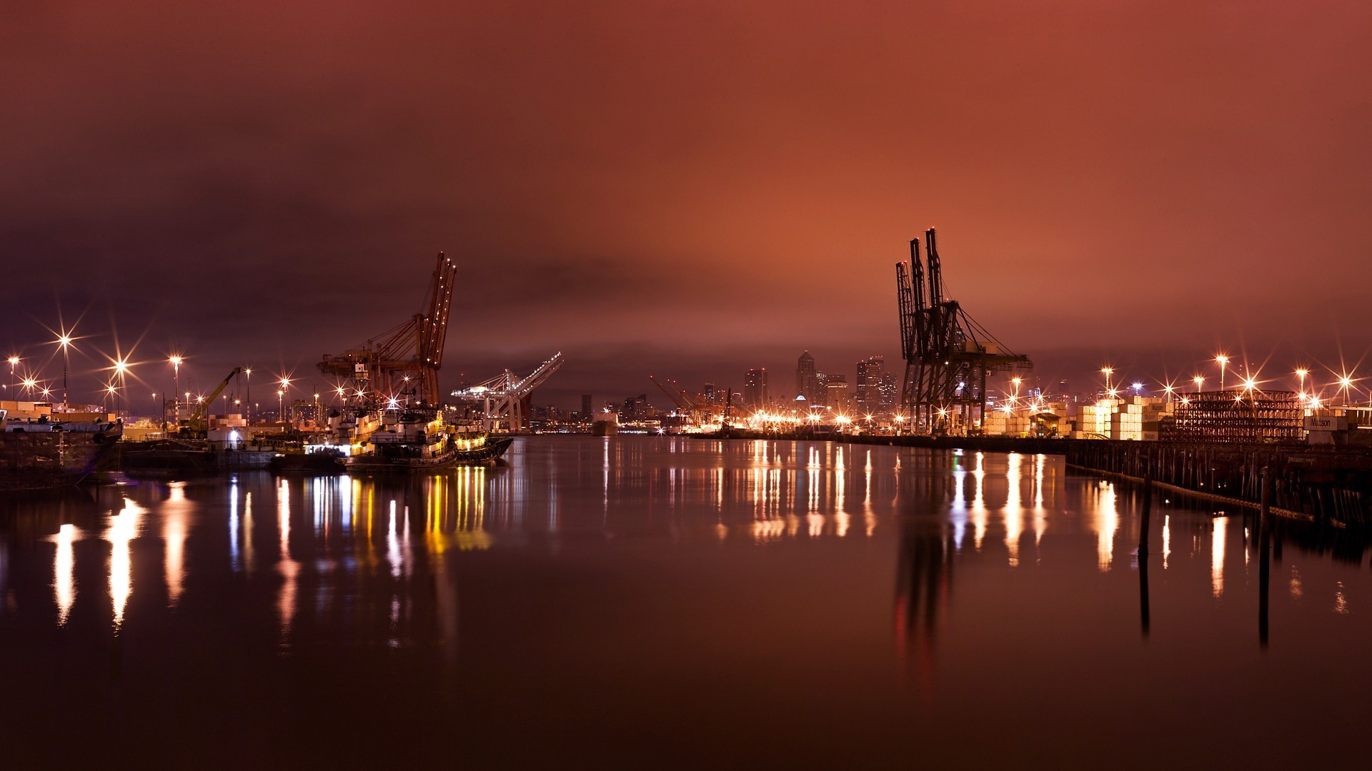 Industrial port with cranes and city skyline at night HD Wallpaper
