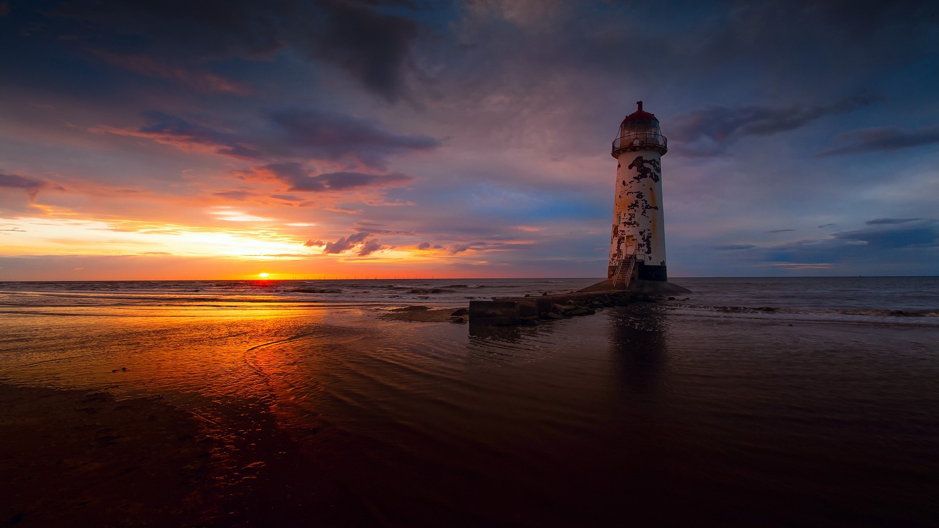Lighthouse on a beach at sunset HD Wallpaper