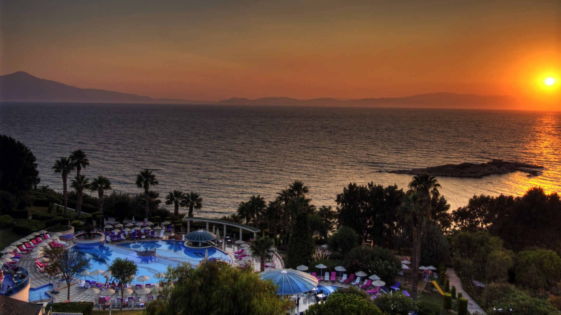 Resort pool and ocean at sunset HD Wallpaper