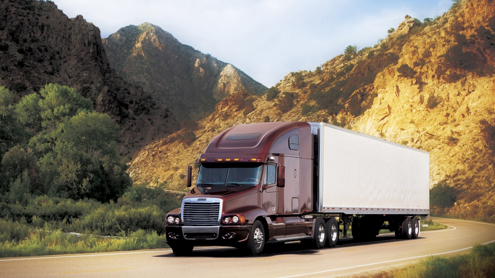 Freightliner semi-truck driving on a mountain road HD Wallpaper