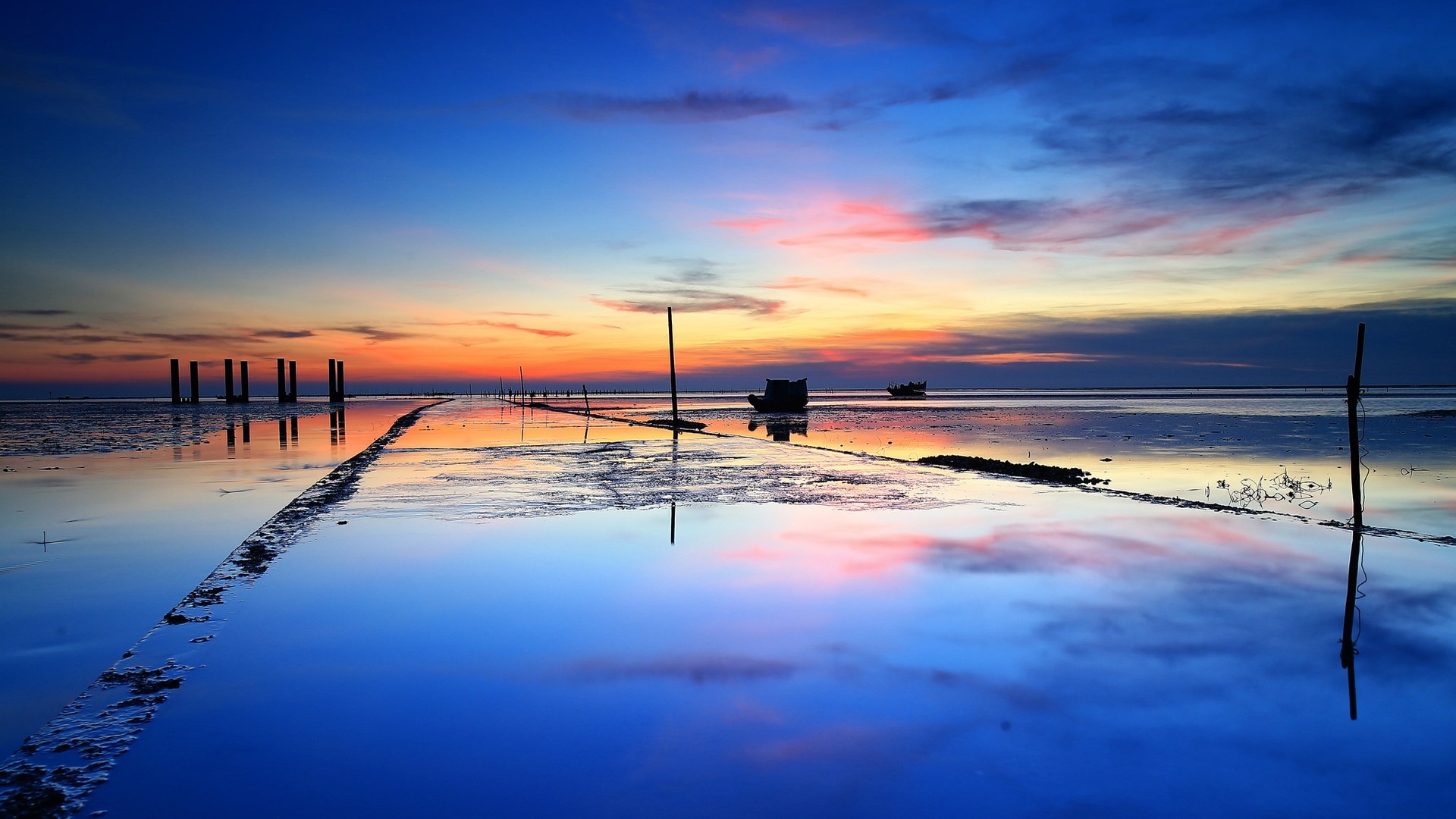 Sunset over a calm sea with reflections and boats HD Wallpaper