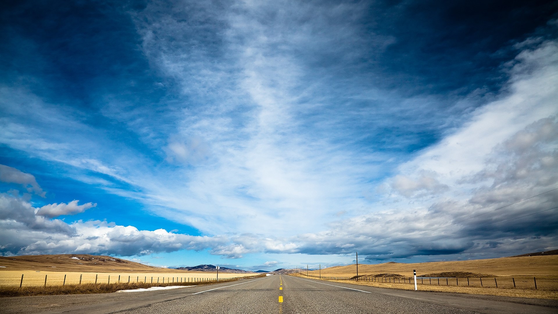 Highway under a vast blue sky with clouds HD Wallpaper