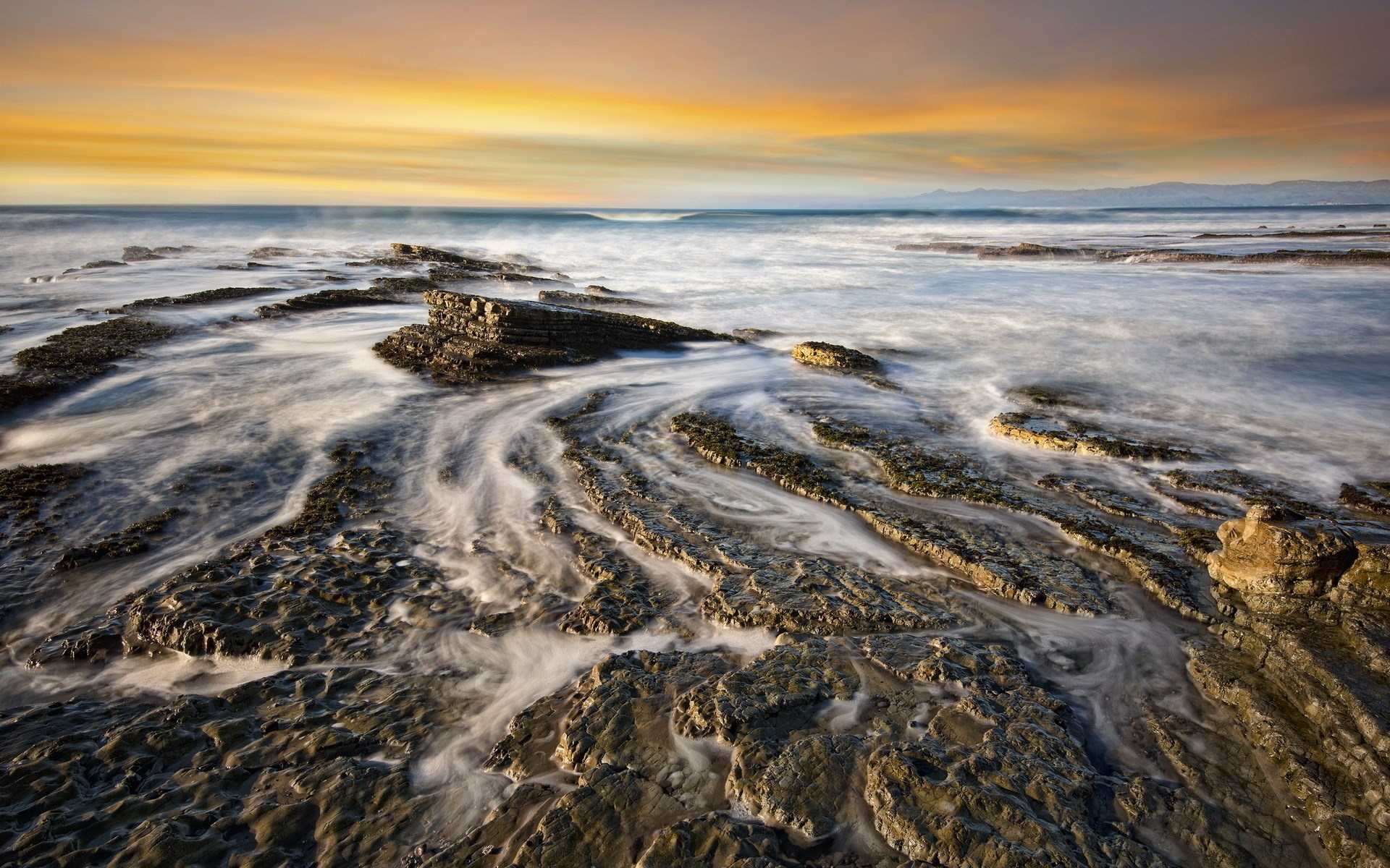 Ocean waves crashing on rocky shore at sunset HD Wallpaper
