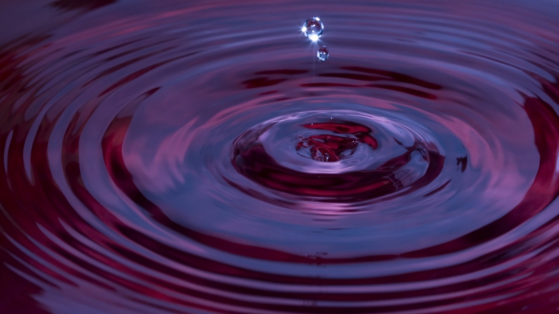 Water drop creating ripples in purple liquid HD Wallpaper