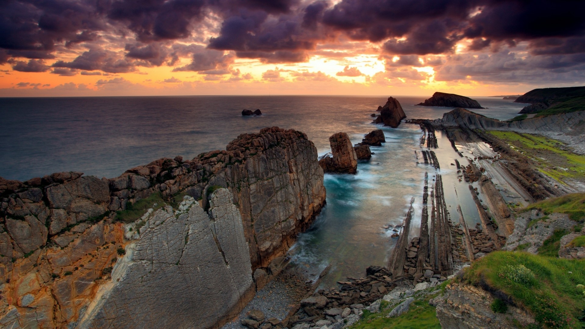 Sunset over rocky coast with dramatic clouds HD Wallpaper