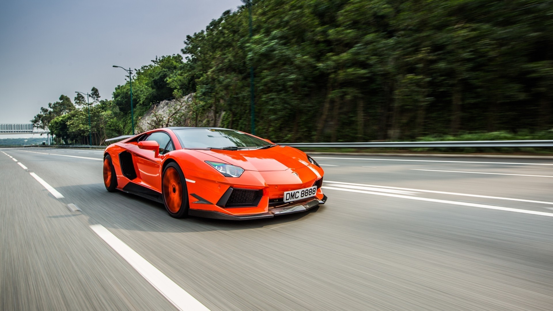 Orange Lamborghini Aventador driving on a road HD Wallpaper
