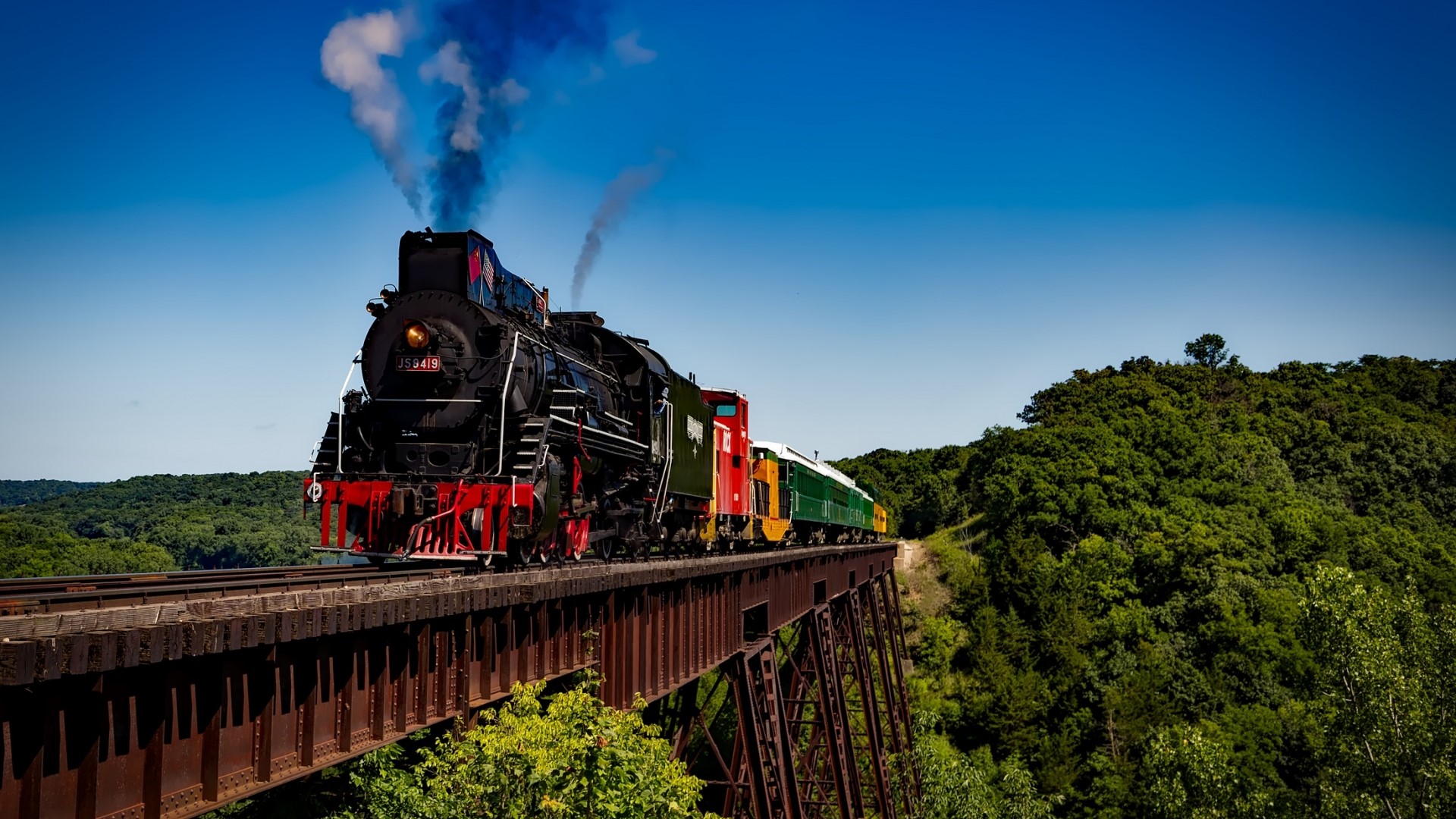 Steam train crossing a bridge over a forest HD Wallpaper