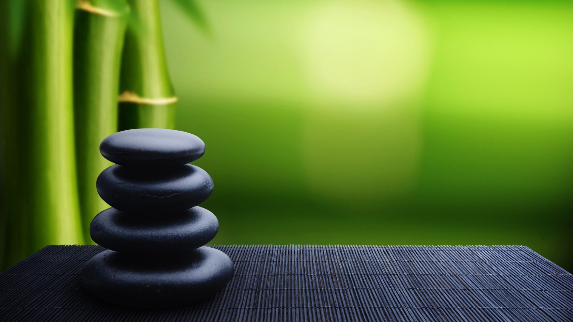 Zen stones stacked on a bamboo mat with bamboo stalks HD Wallpaper