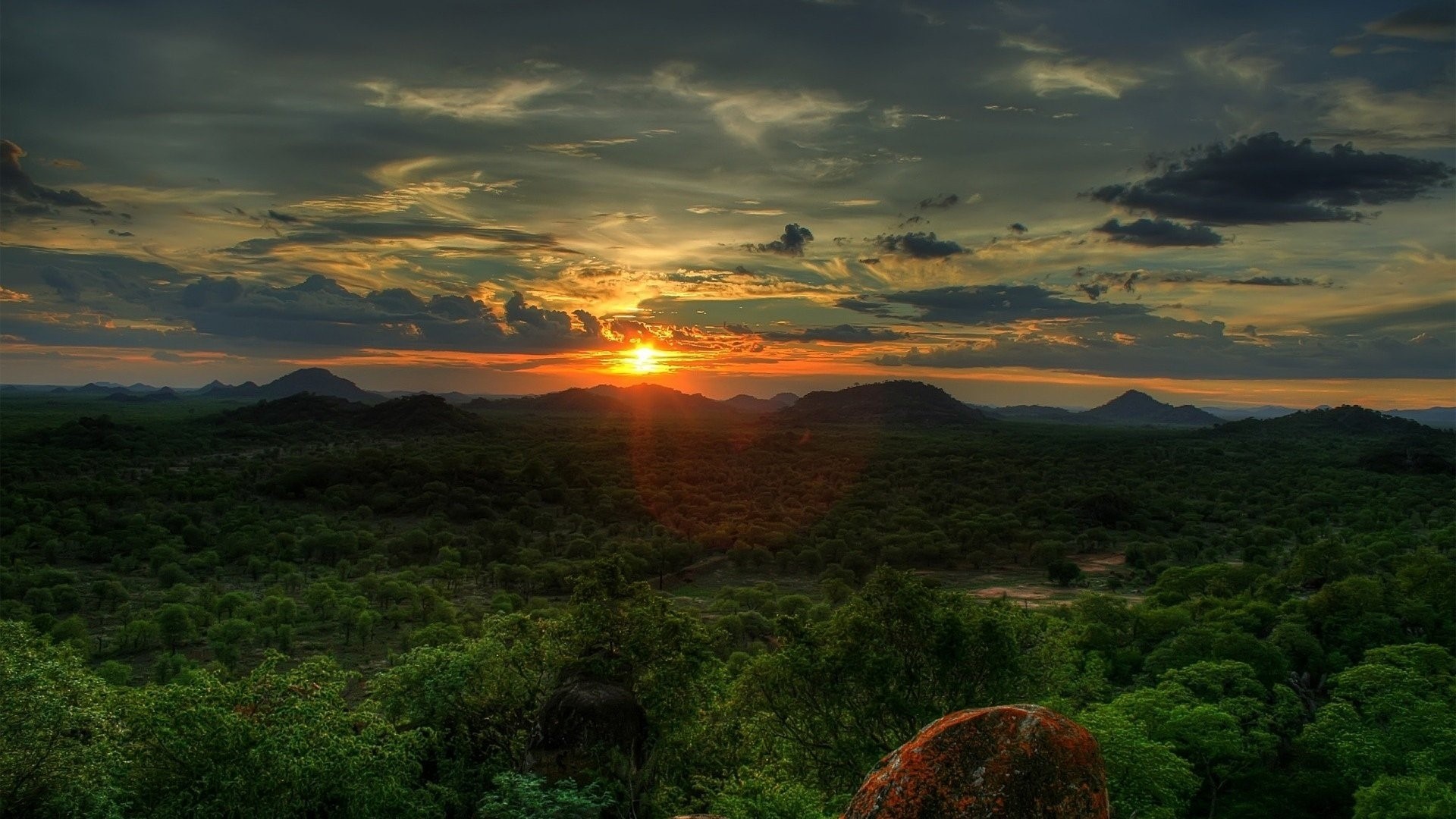 Sunset over a green landscape with mountains HD Wallpaper