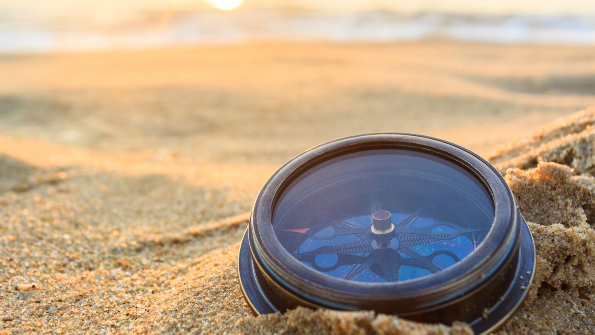 Compass on sand at sunset HD Wallpaper