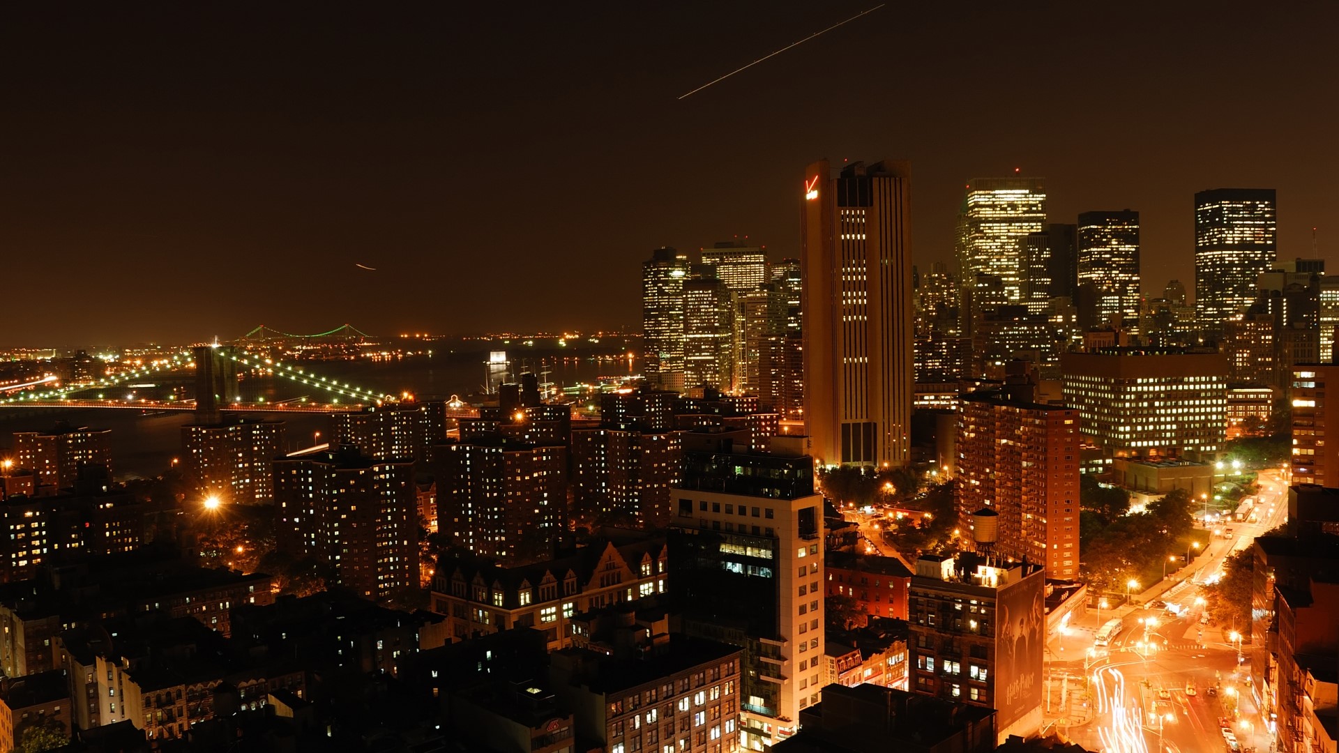 Nighttime cityscape of Manhattan with bridge and airplane contrail HD Wallpaper