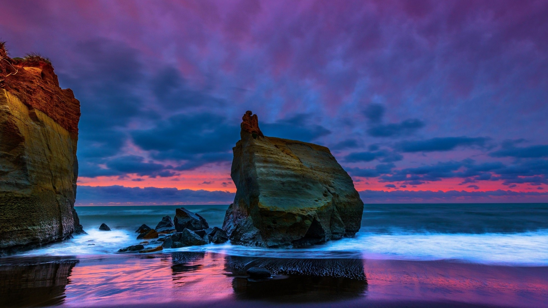 Sunset over a rocky beach with purple clouds HD Wallpaper