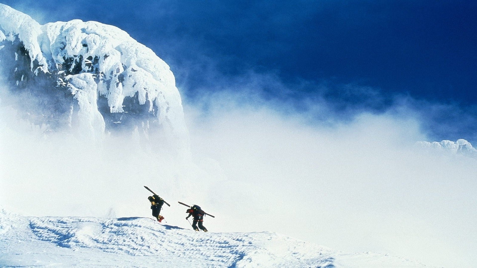 Two skiers ascend a snowy mountain slope near Mount Hood. HD Wallpaper