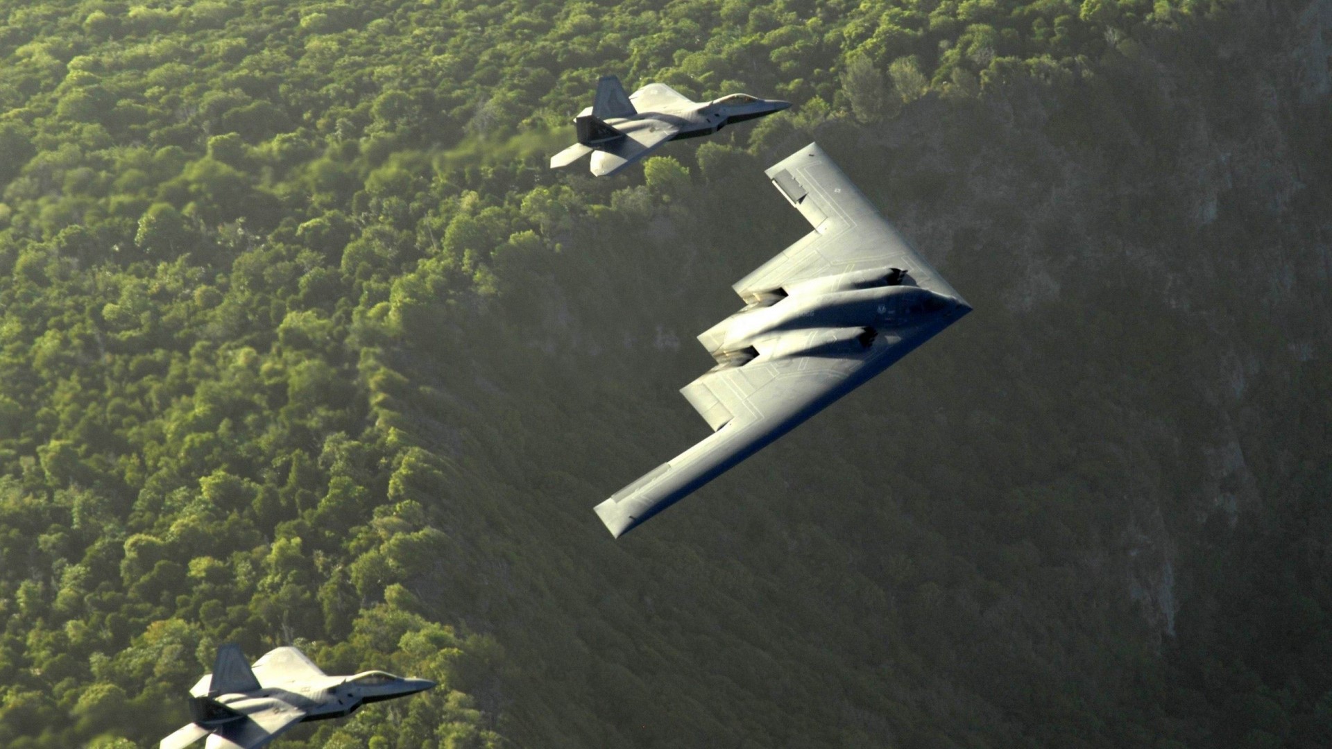 B-2 Spirit and F-22 Raptors flying over forest HD Wallpaper