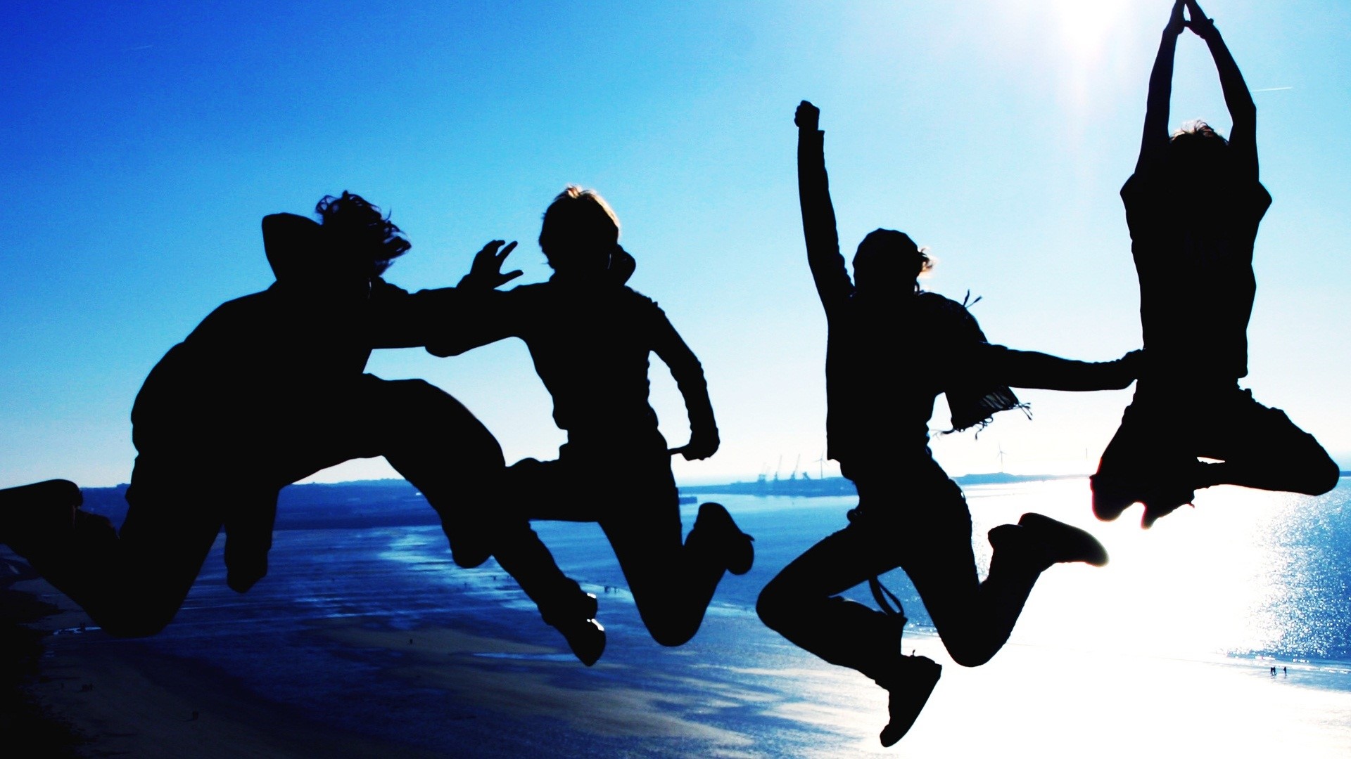 Four friends jumping on a beach at sunset HD Wallpaper