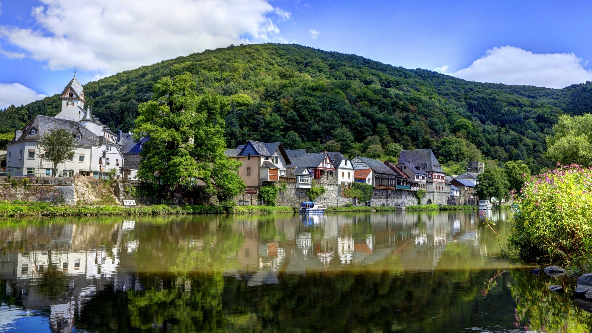 River town with green hills and cloudy sky HD Wallpaper