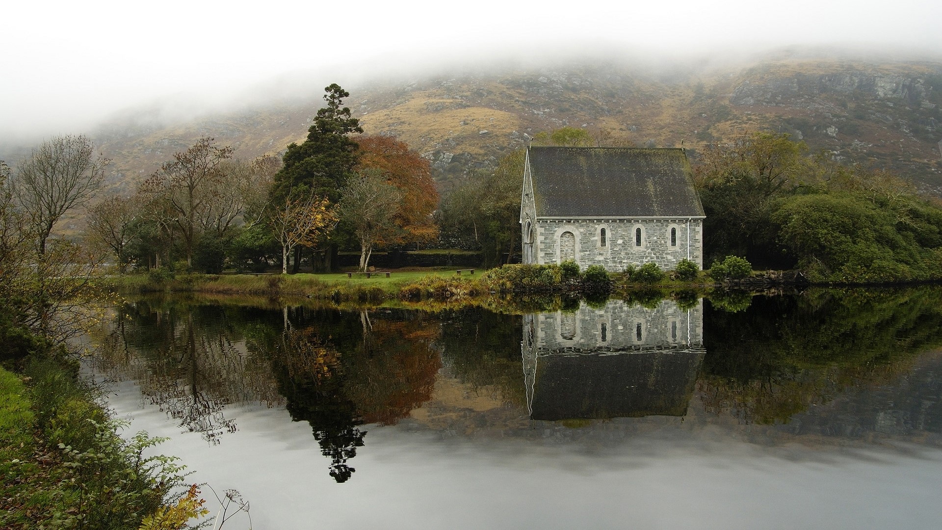 Stone building by a lake with misty mountains HD Wallpaper