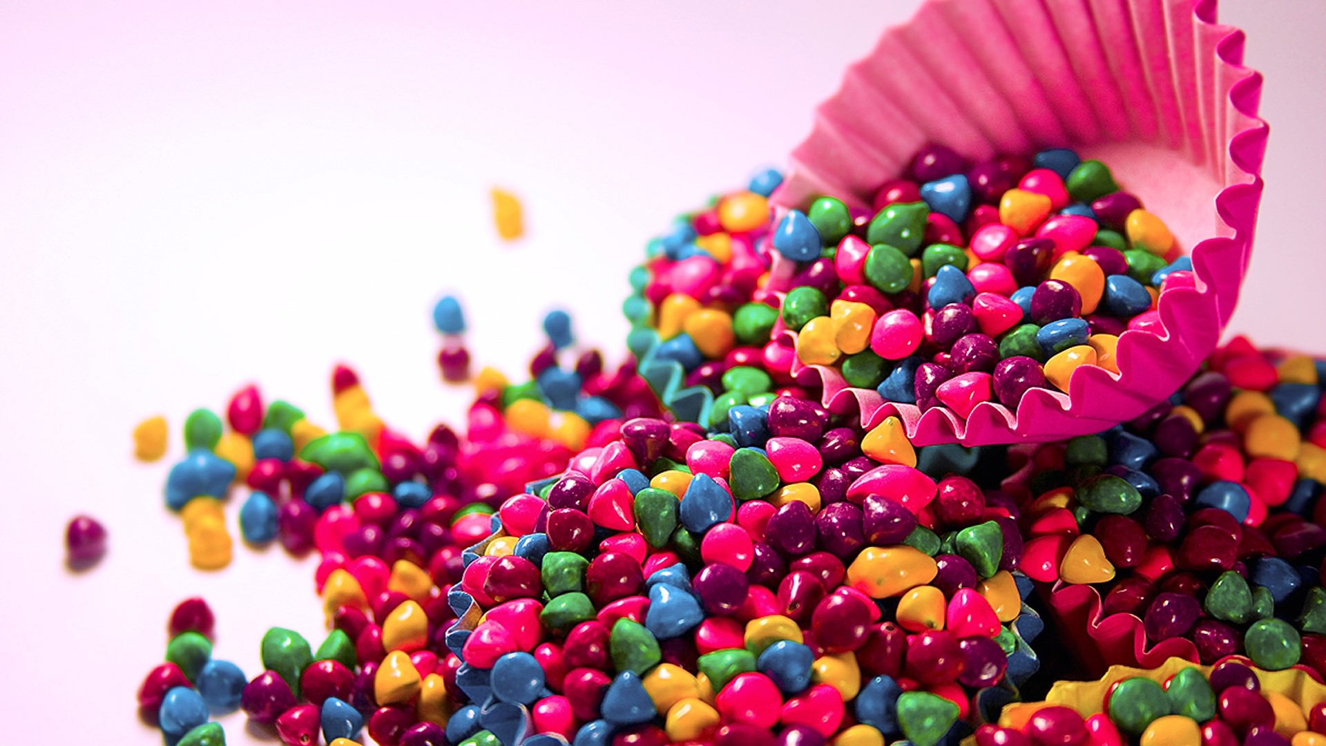 Colorful candies spilling from a pink cupcake liner HD Wallpaper
