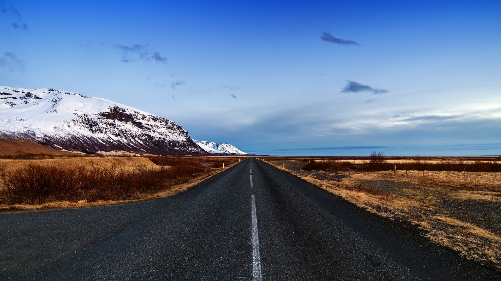 Road through Icelandic landscape with snow-capped mountains HD Wallpaper