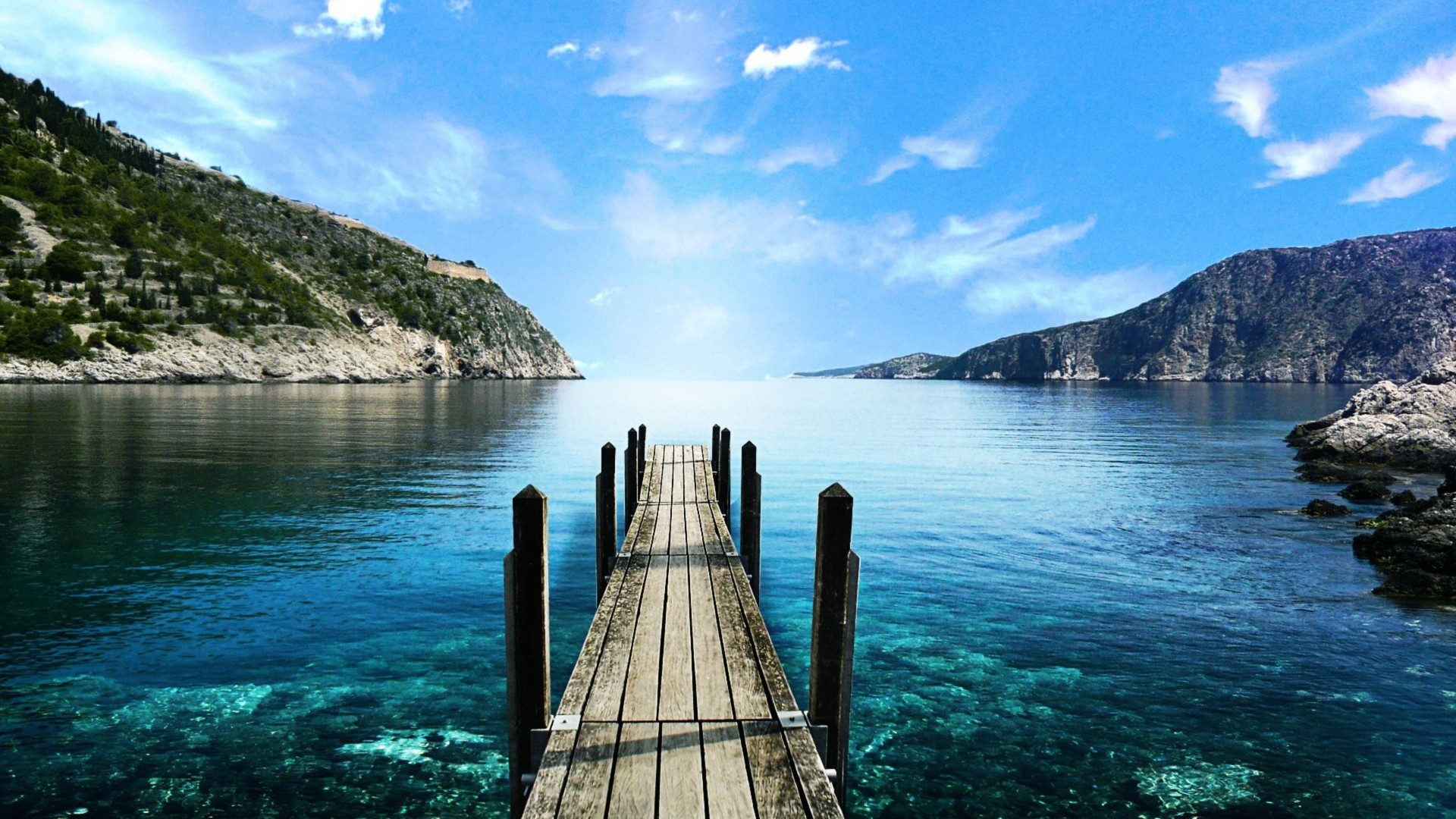 Wooden dock on clear blue water with mountains HD Wallpaper