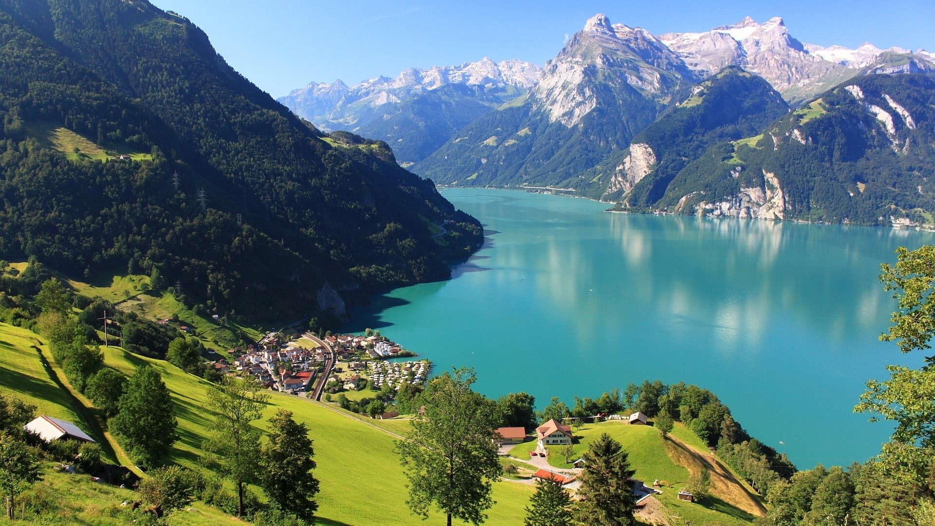 Turquoise lake surrounded by mountains and green hills HD Wallpaper