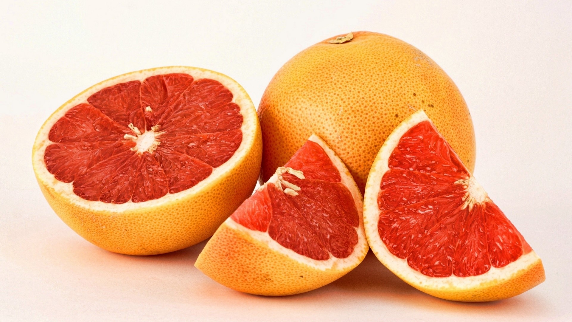 Sliced and whole grapefruits on a white background HD Wallpaper