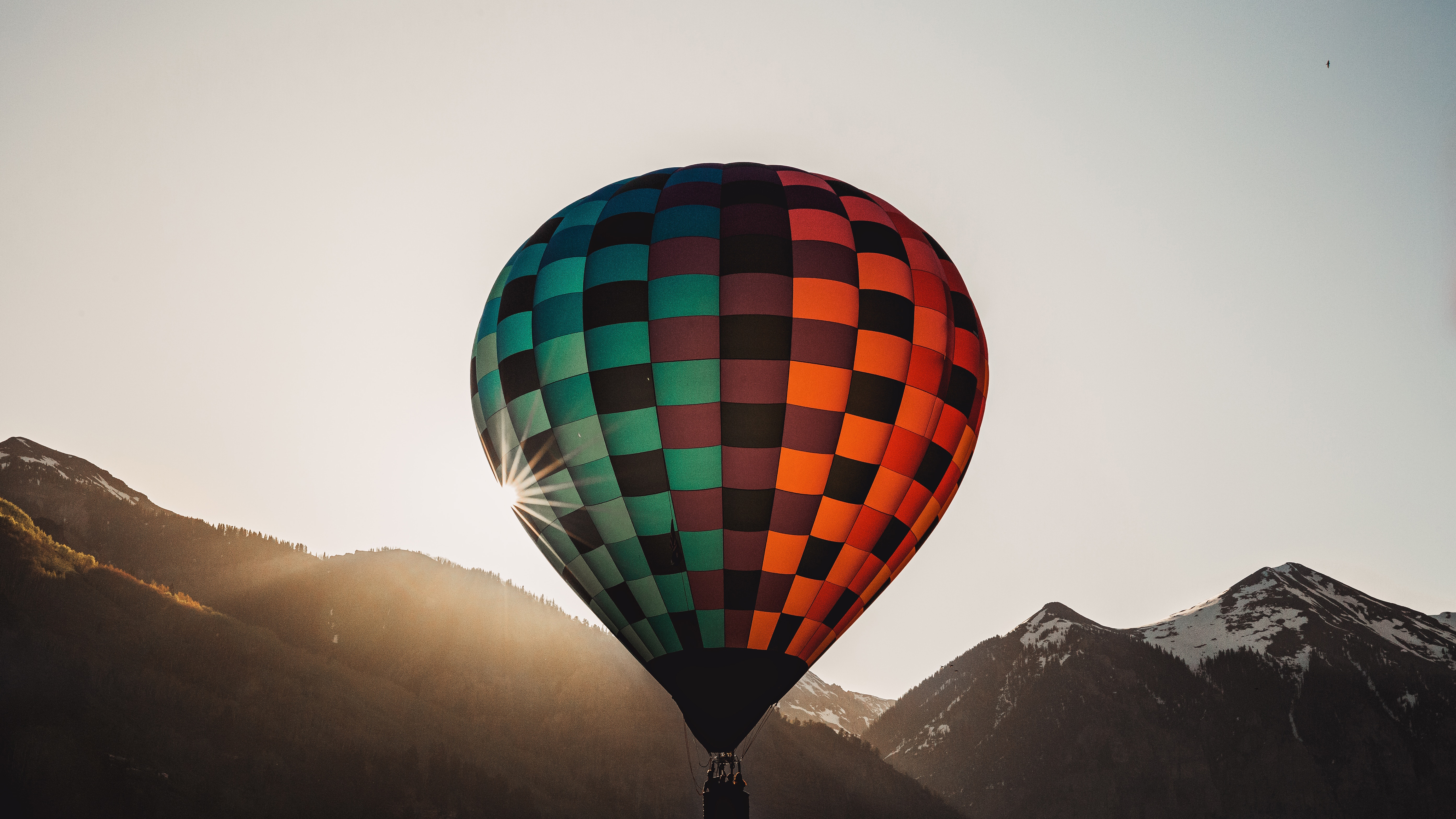 Hot air balloon flying over mountains at sunset HD Wallpaper