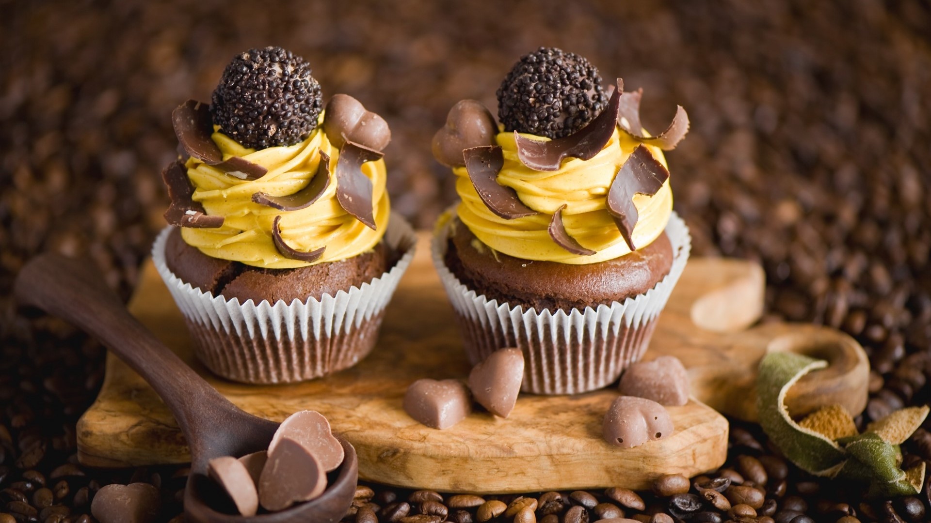 Two chocolate cupcakes with yellow frosting and chocolate decorations HD Wallpaper