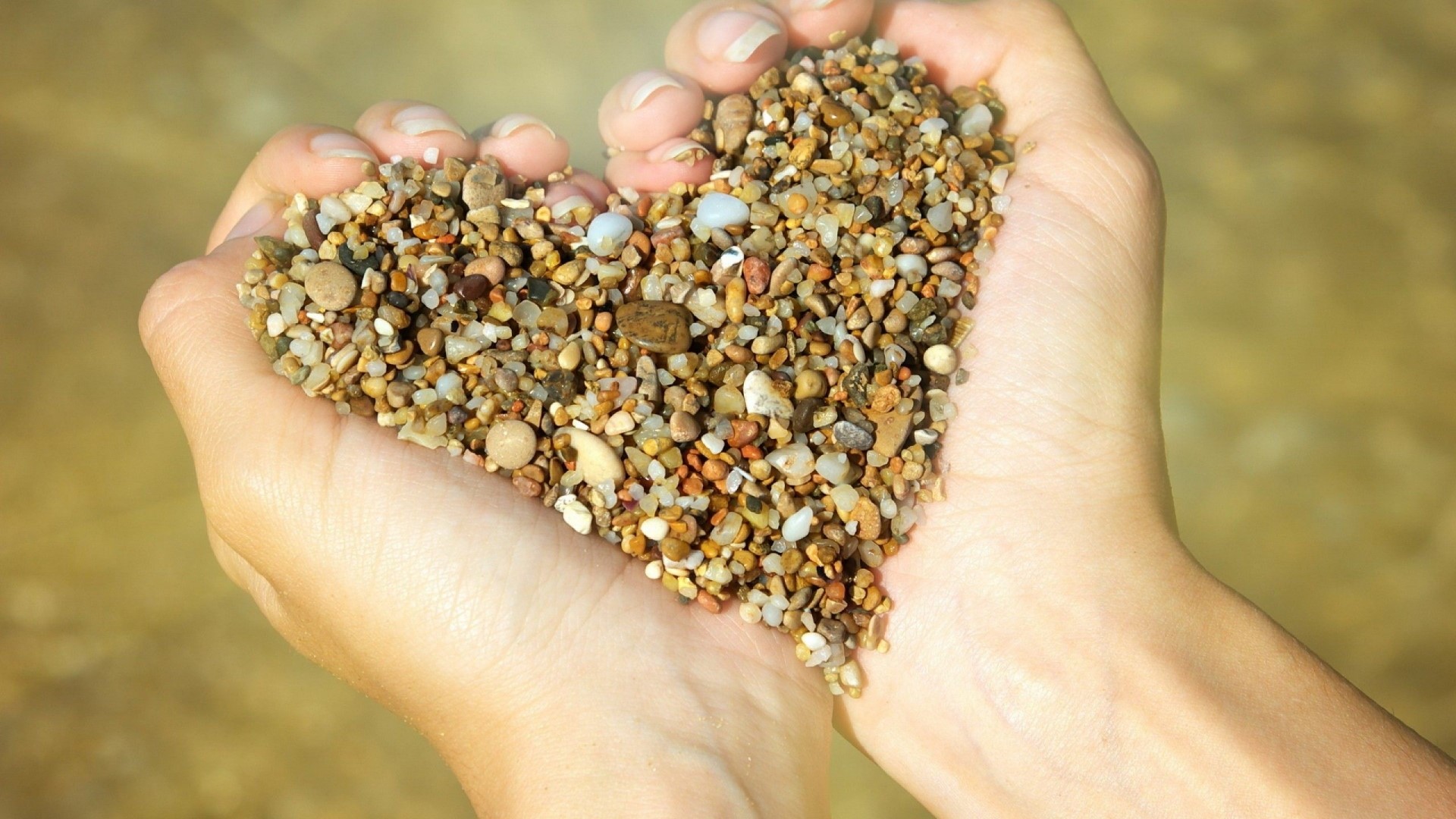 Hands holding a heart shape of stones HD Wallpaper