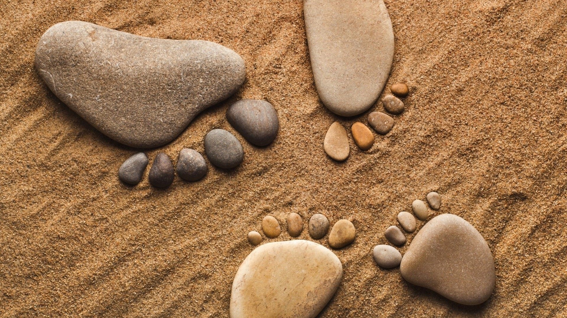Footprints made of stones on sand HD Wallpaper